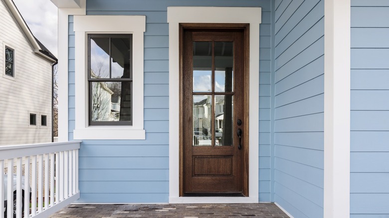 Brown front door of a house house siding blue vinyl